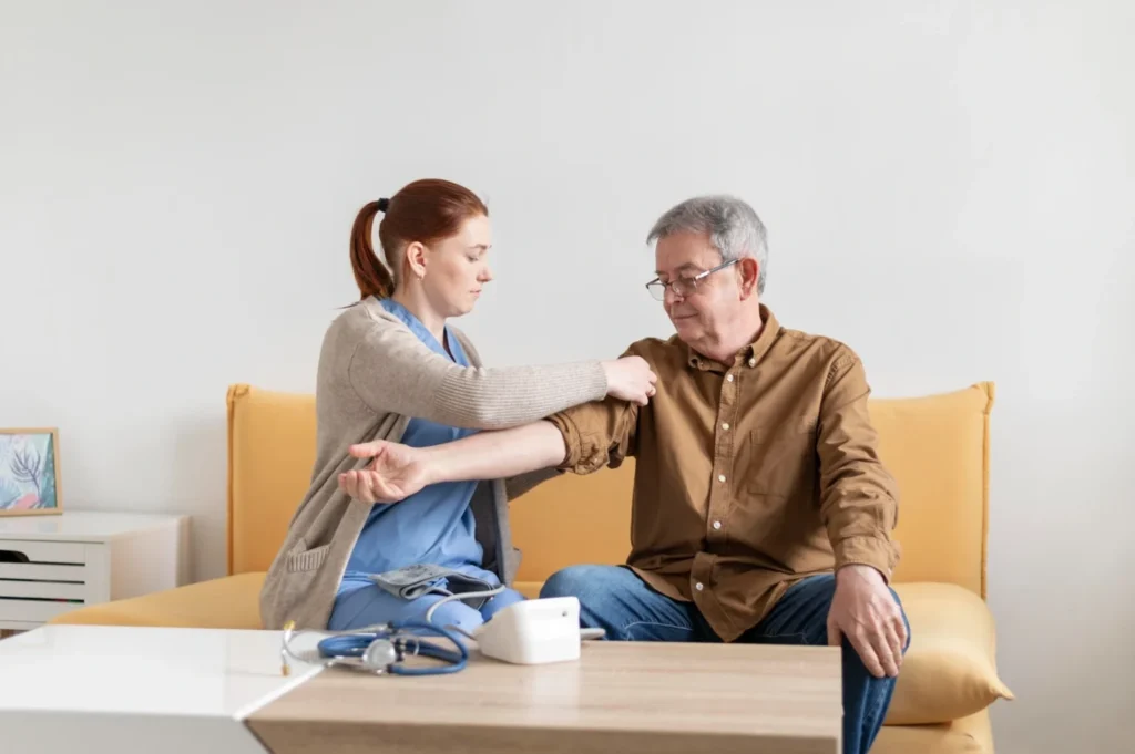 Healthcare professional preparing to check an older man’s blood pressure